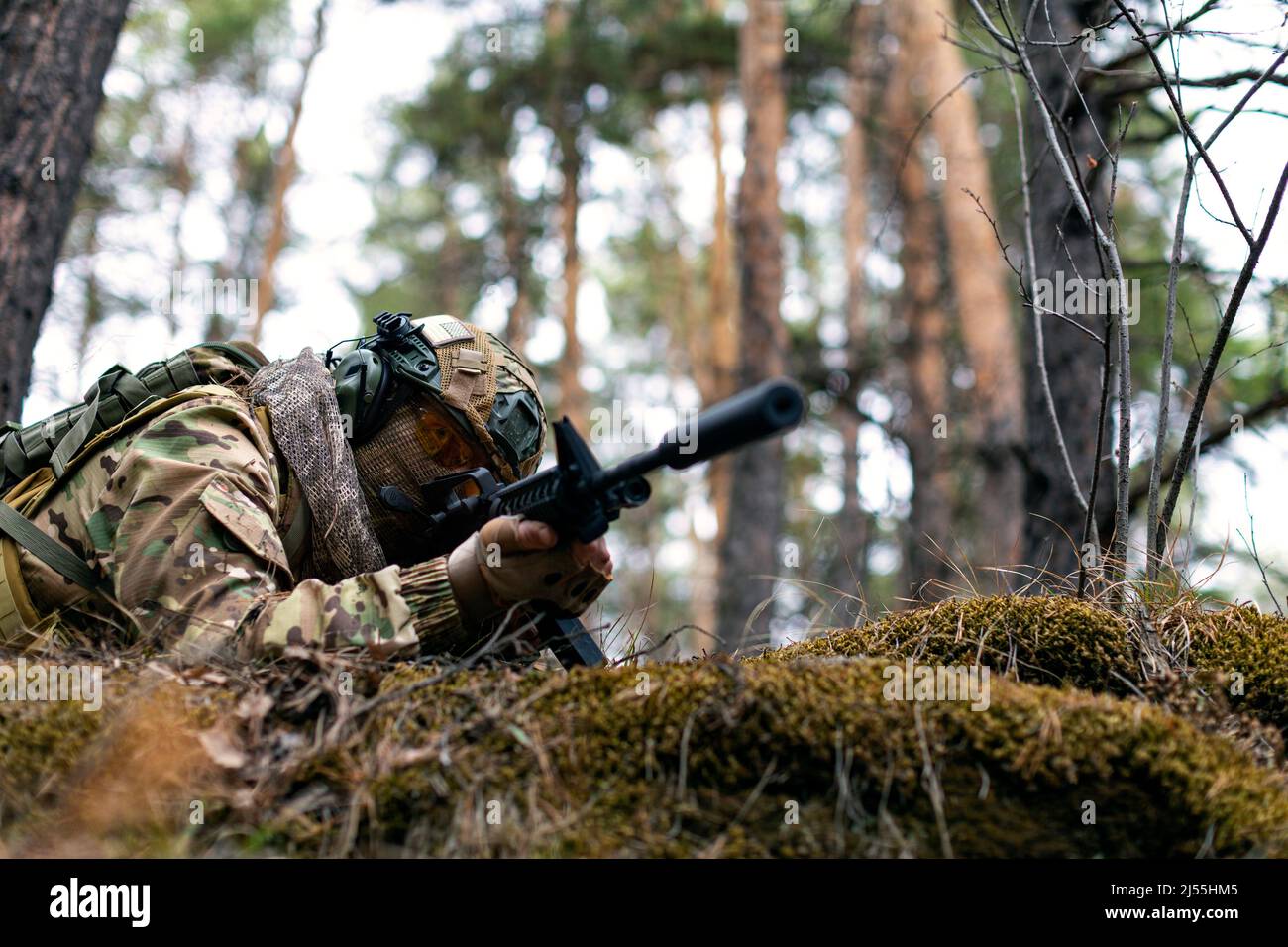 Photo of a soldier aims at the enemy during a clash in the forest. The concept of modern warfare and special forces. Cropped image. Stock Photo