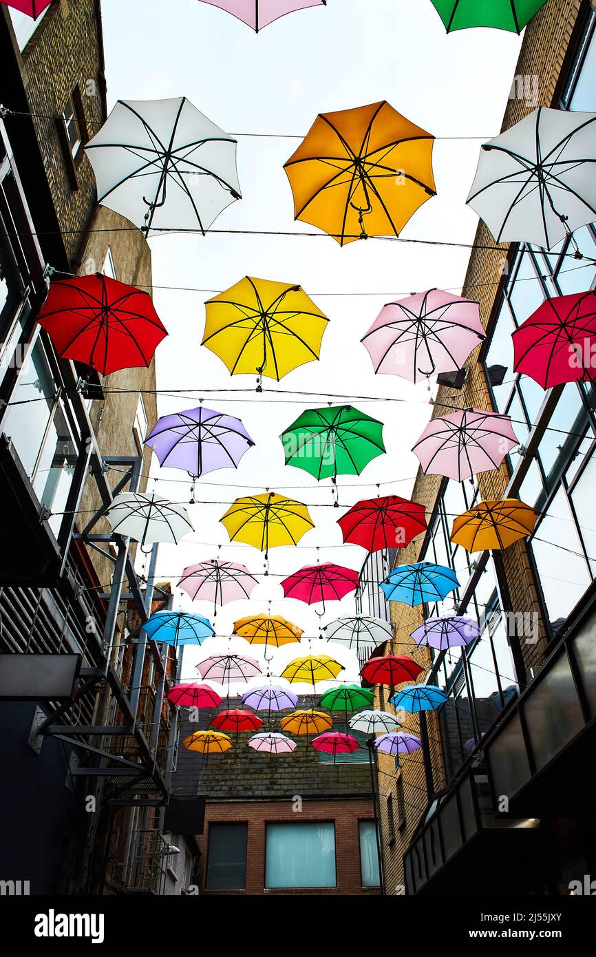 Cloudy sky and a lot of multi colored umbrellas on top of street in