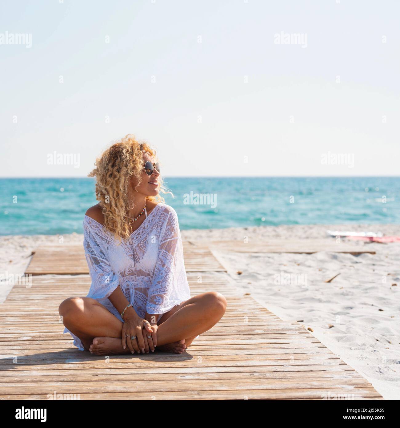 Happy female people tourist witting on a wooden pier at the beach on the sand enjoying summer holiday vacation and amazing tropical destination. Blue Stock Photo