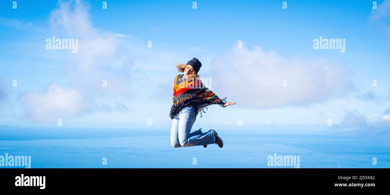 Woman overjoyed jumping crazy for happiness. Concept of freedom and joyful. Female people in leisure activity and fun with blue sky and ocean inbackgr Stock Photo