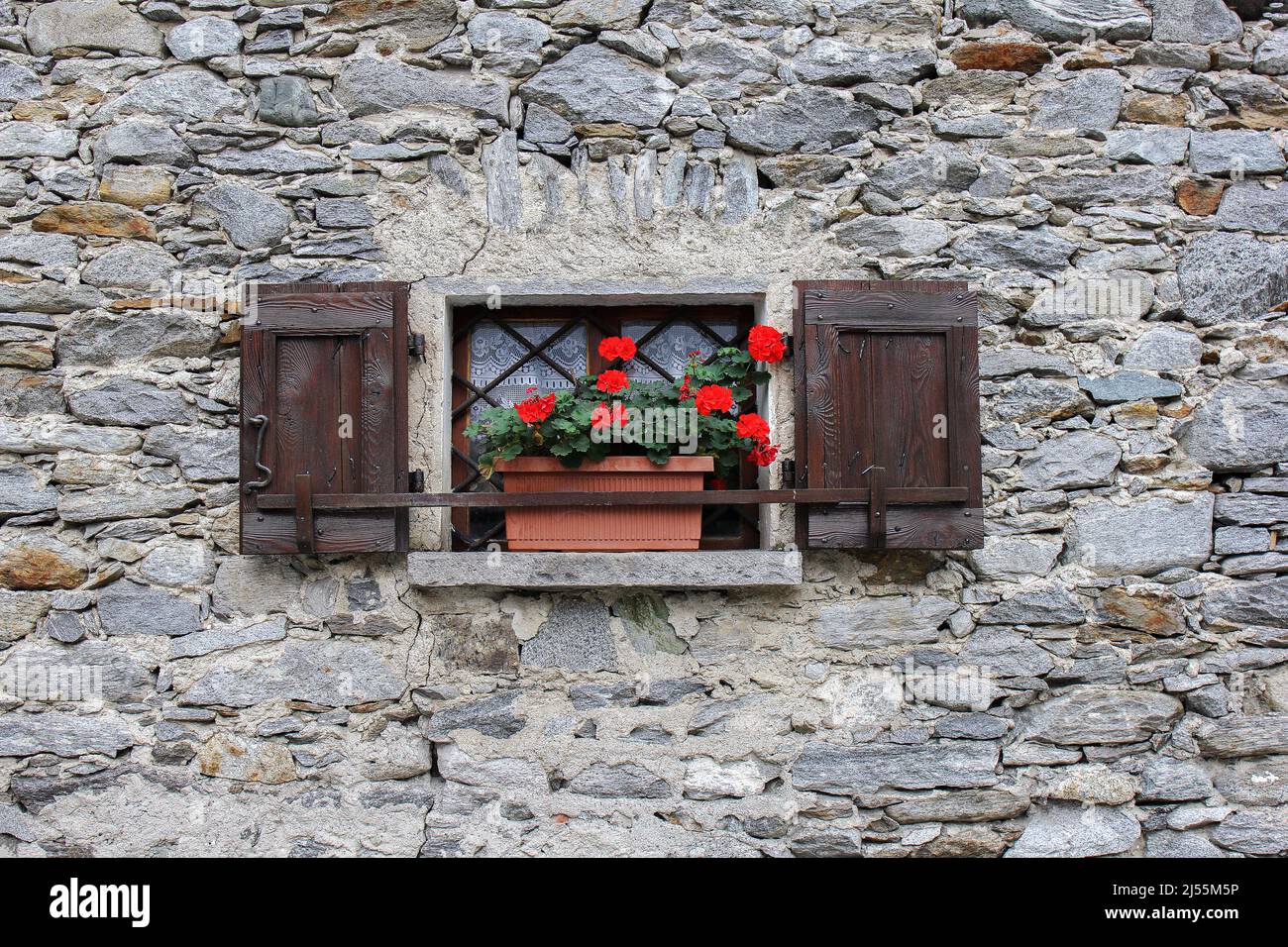 Window with red geranium on a stone house Stock Photo - Alamy