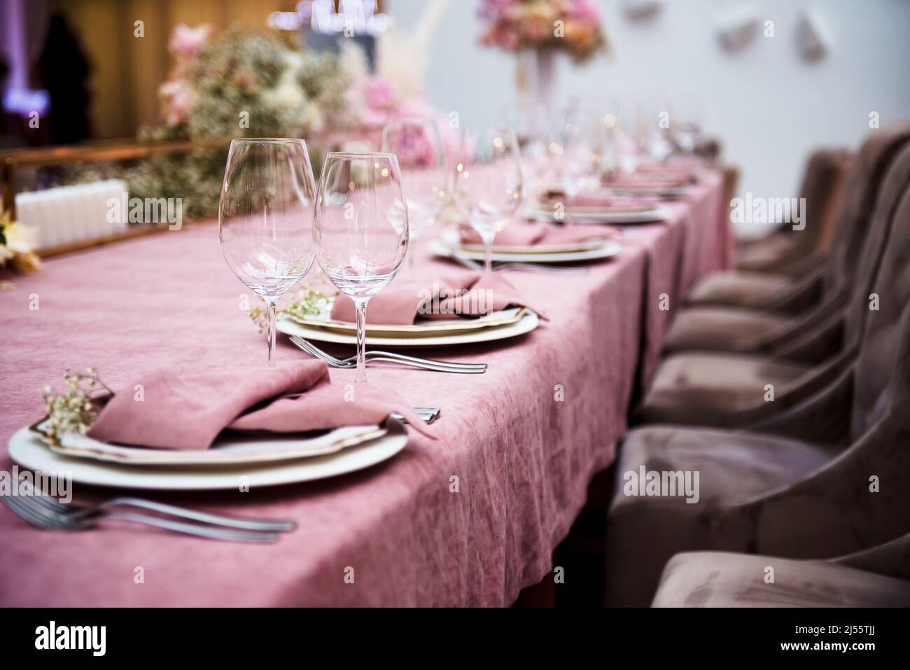 Beautiful table set with plates, empty wineglasses, pink napkins, and cutlery. Elegant stylish decor adding sophistication to wedding interior. Stock Photo
