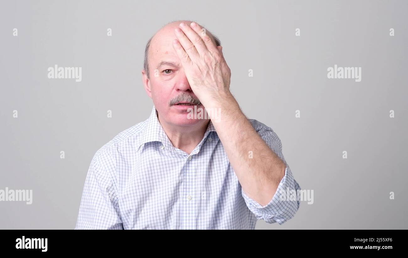 Tired european man covering one eye with palm as if having his eyes ...