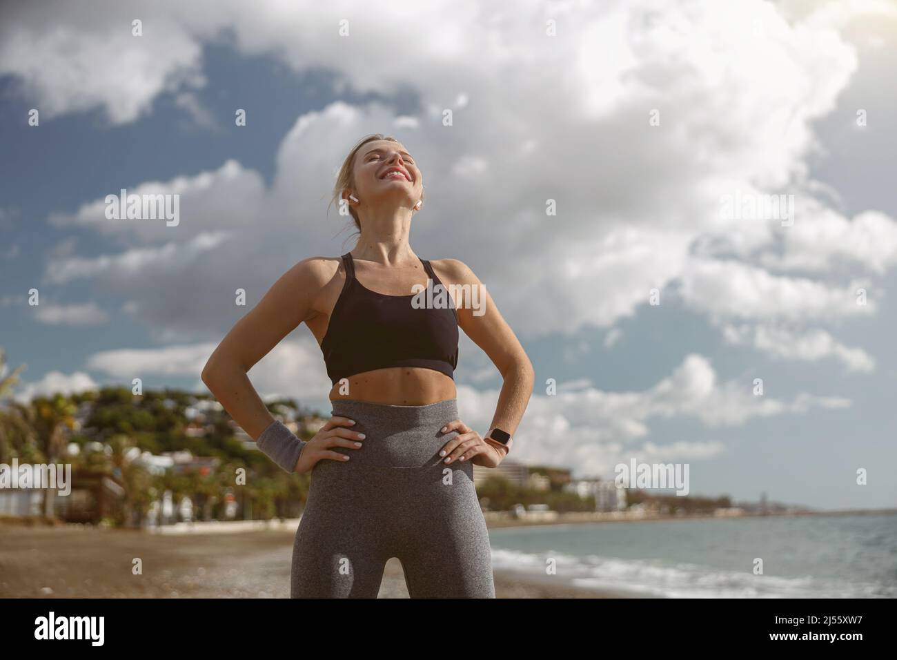 Young sportswoman relaxing while standing on beach Stock Photo