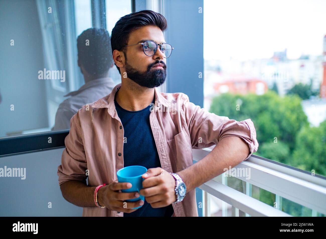 arabian man in casual dress holning a blue cup and looking dreamly Stock Photo
