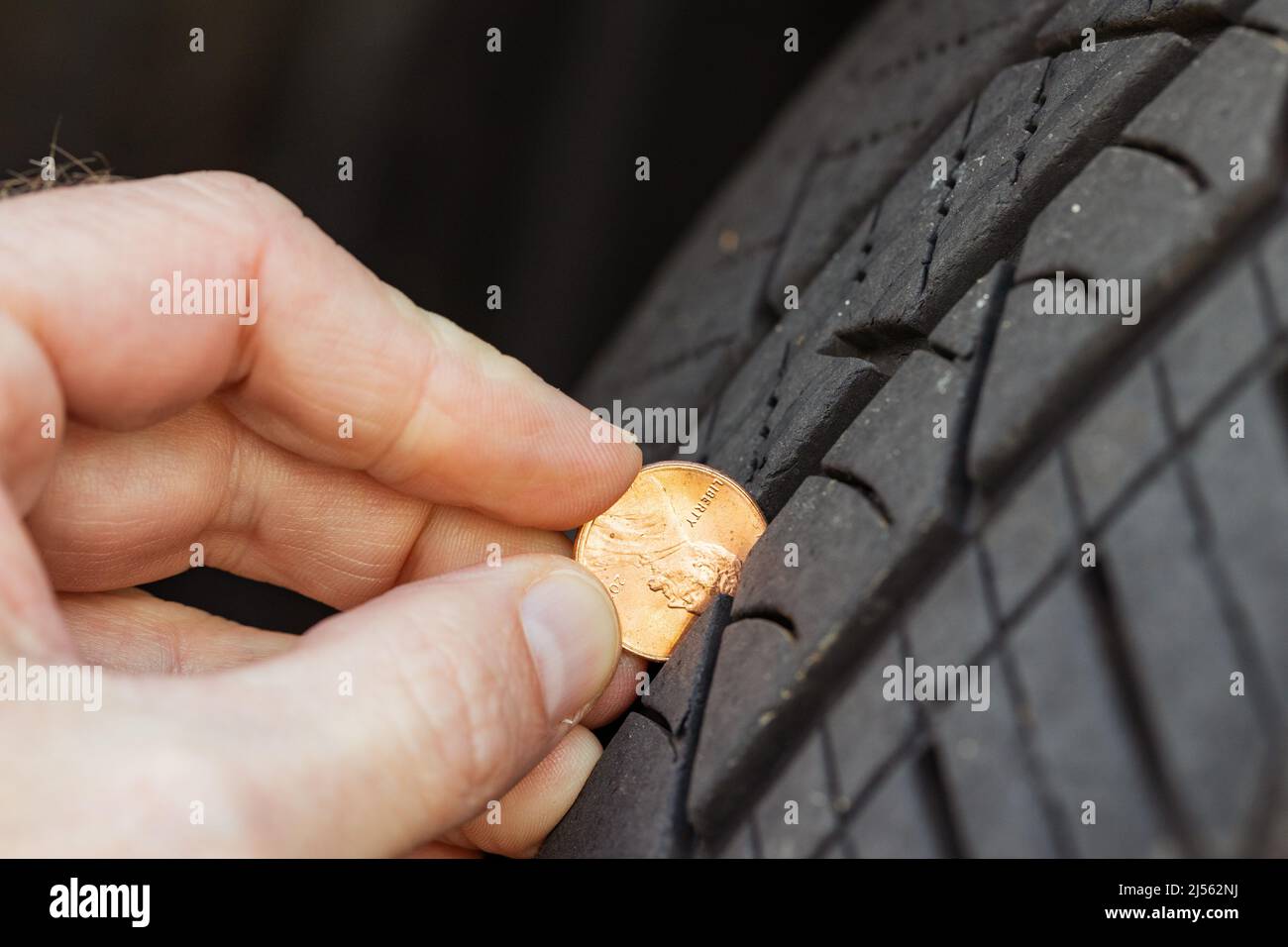 Checking tread depth on a tire by using a penny Stock Photo
