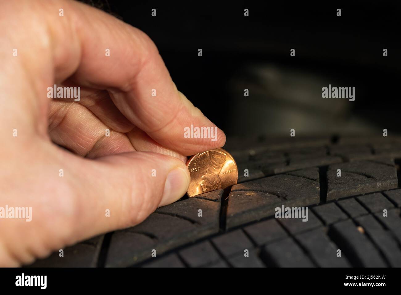 Using a penny to check tread depth on a tire Stock Photo