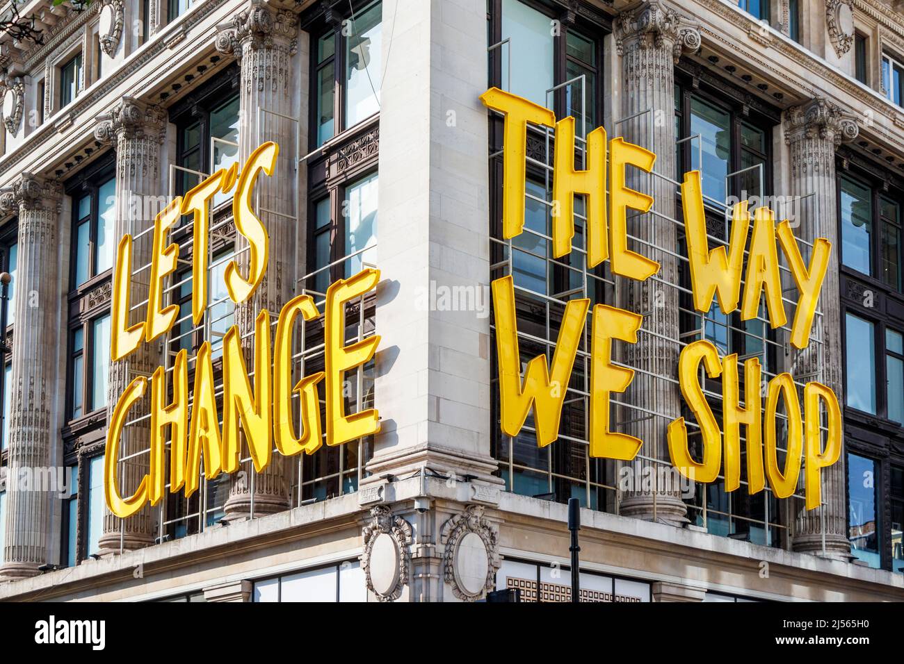 A sign on the corner of the Selfridges store in Oxford Street with the phrase 'Let's Change The Way We Shop', London, UK Stock Photo