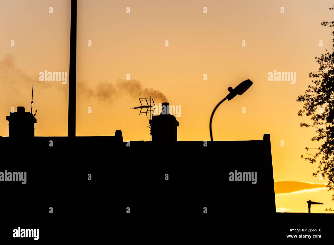 Smoke rising from a house chimney in Ireland at sunset. Stock Photo