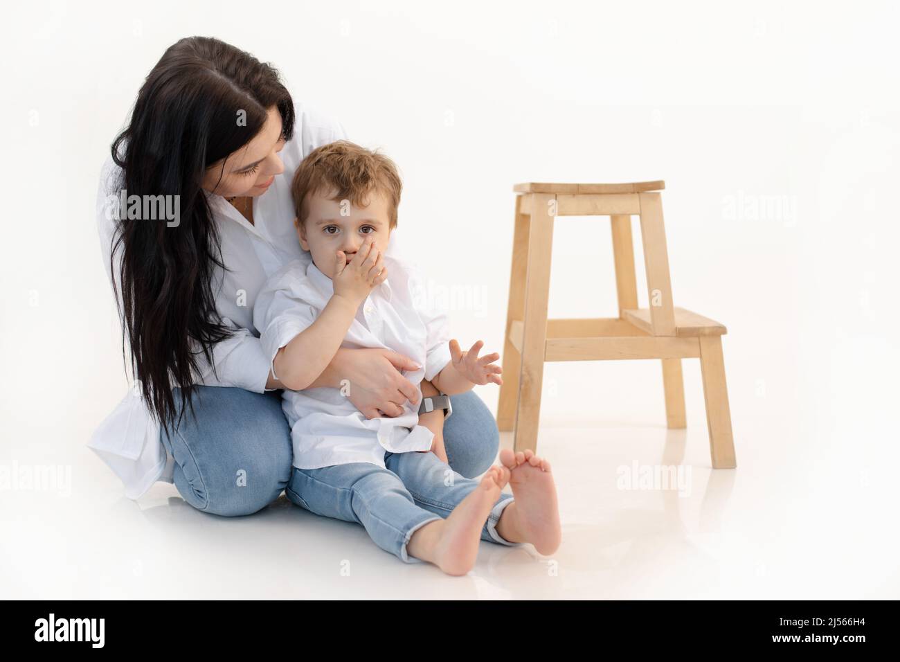 Caring woman and boy hugging, spending time together. Close bounding between mother and son, quieting, sitting on floor Stock Photo