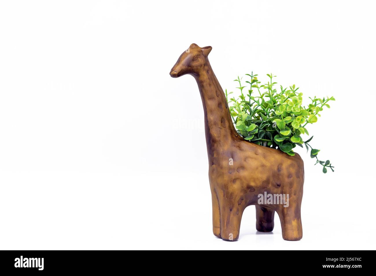Wooden figurine of a giraffe with green plants on the back. Stock Photo