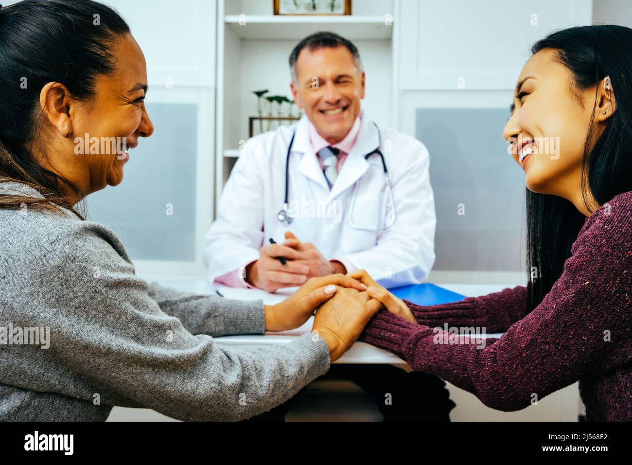 smiling doctor and happy adult female patients in doctor's office healthcare industry Stock Photo