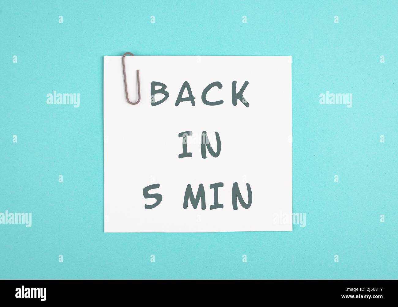 Back in 5 min is standing on a paper, working break, be right back, message in the office Stock