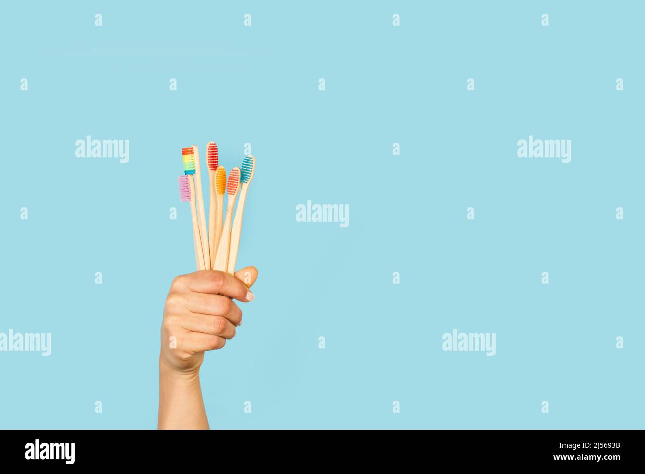Woman hand holding bamboo toothbrushes on a light blue background Stock ...