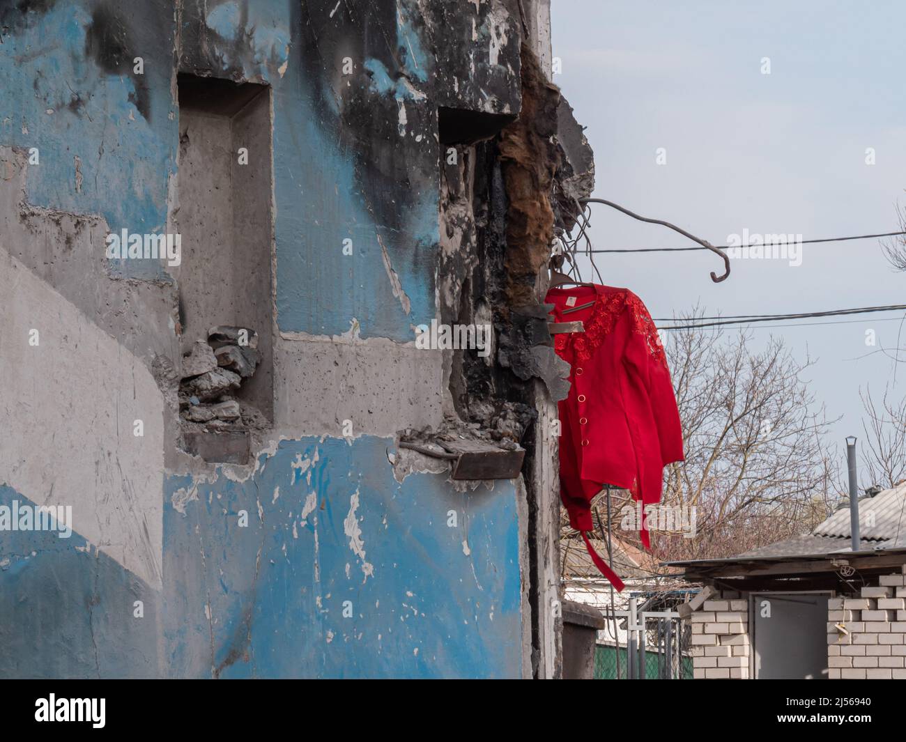 Russia's war against Ukraine. Russian bomb hit civilian buildings. War in Ukraine, ruined building after bombing. Red women's jacket against the background of a bombed-out house Stock Photo