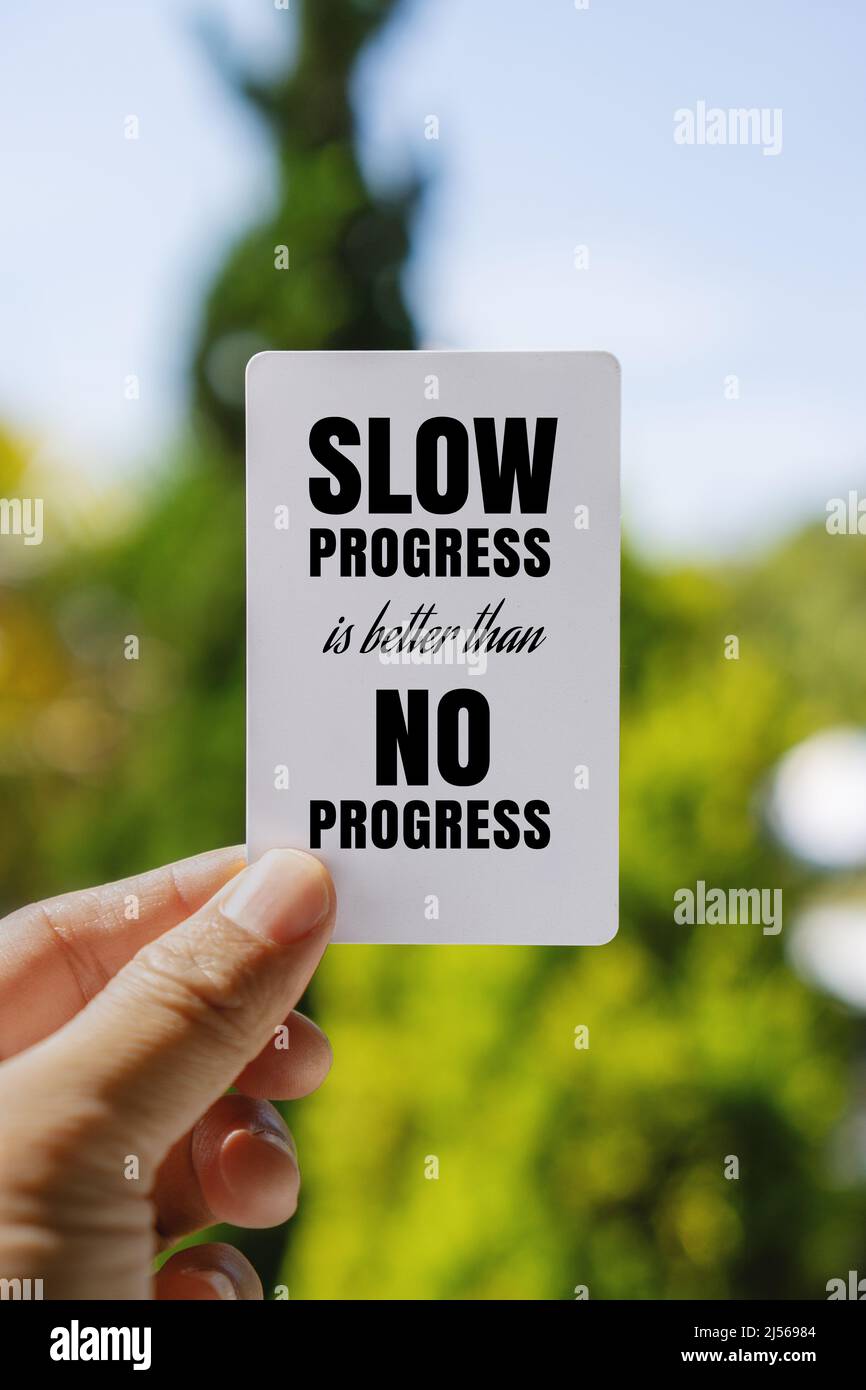 Hand Holding White Paper Card Against Fresh Nature Background. Inspirational Quote. Slow Progress is Better Than No Progress. Stock Photo