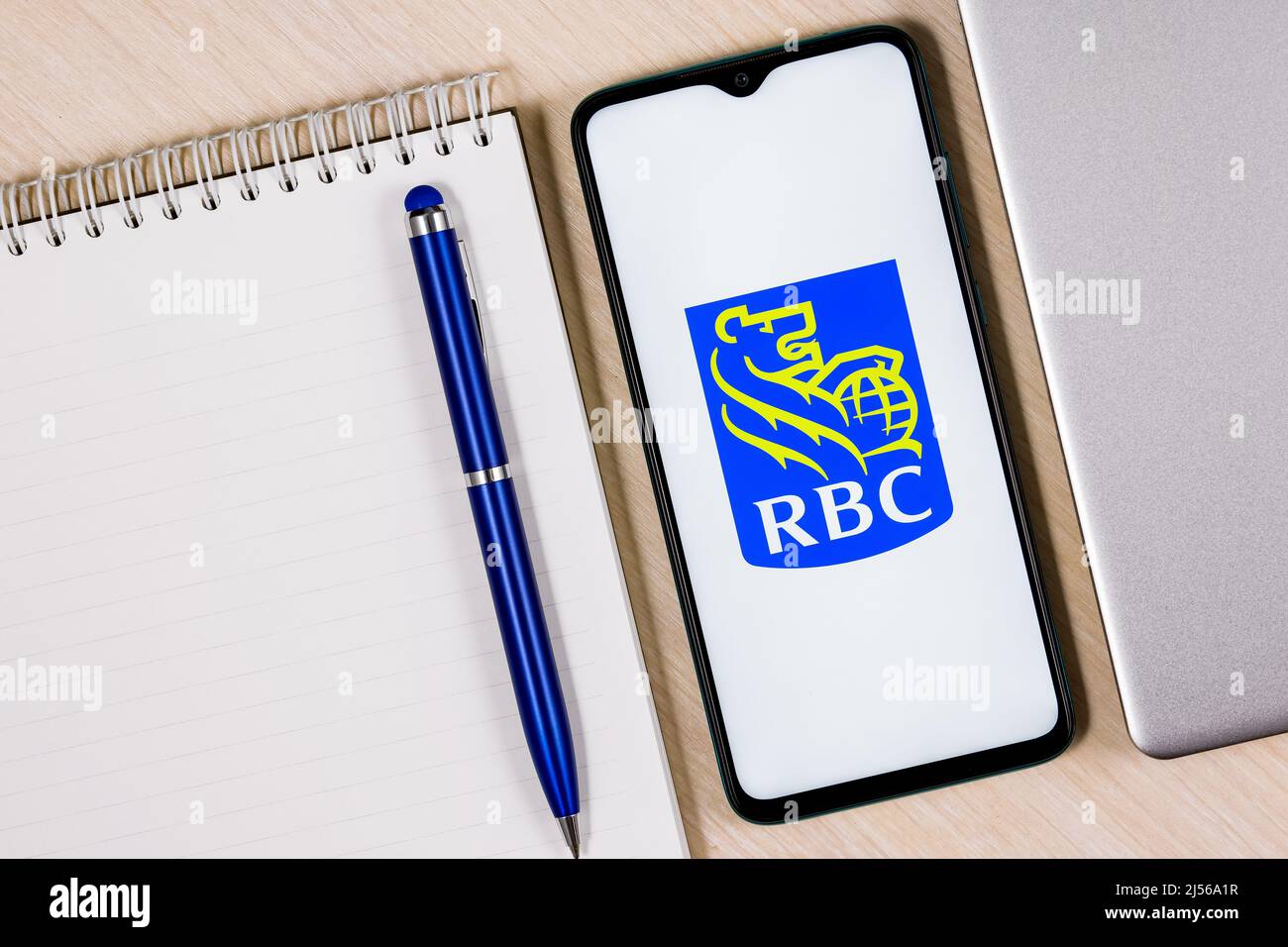 Smartphone with Royal Bank of Canada logo on wooden table next to laptop and business planner Stock Photo