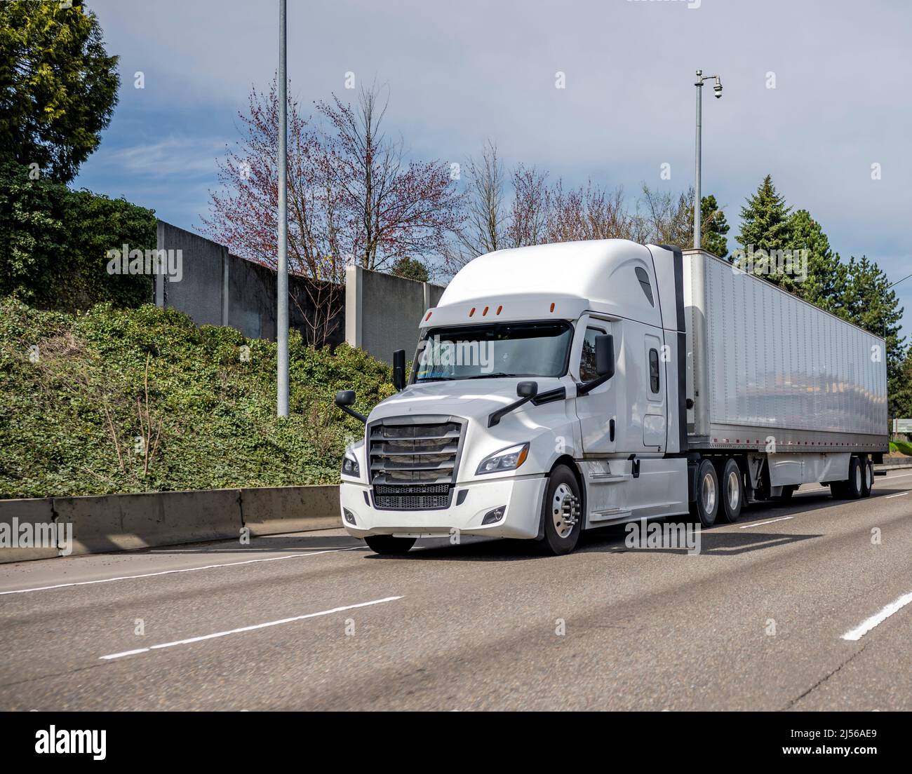 Industrial powerful long haul white big rig semi truck tractor transporting cargo in dry van semi trailer running on the straight wide highway road wi Stock Photo