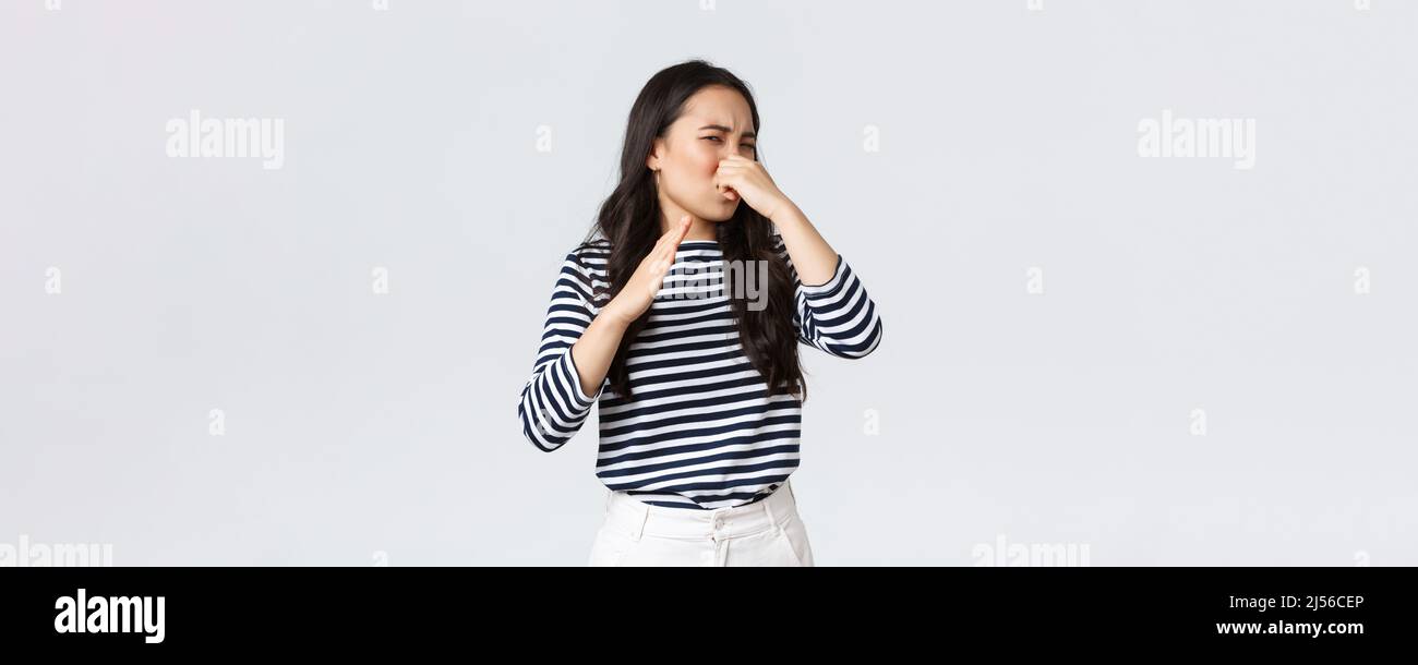 Lifestyle, beauty and fashion, people emotions concept. Disgusted korean girl shut nose and waving hand from disgust and aversion as sniff awful Stock Photo