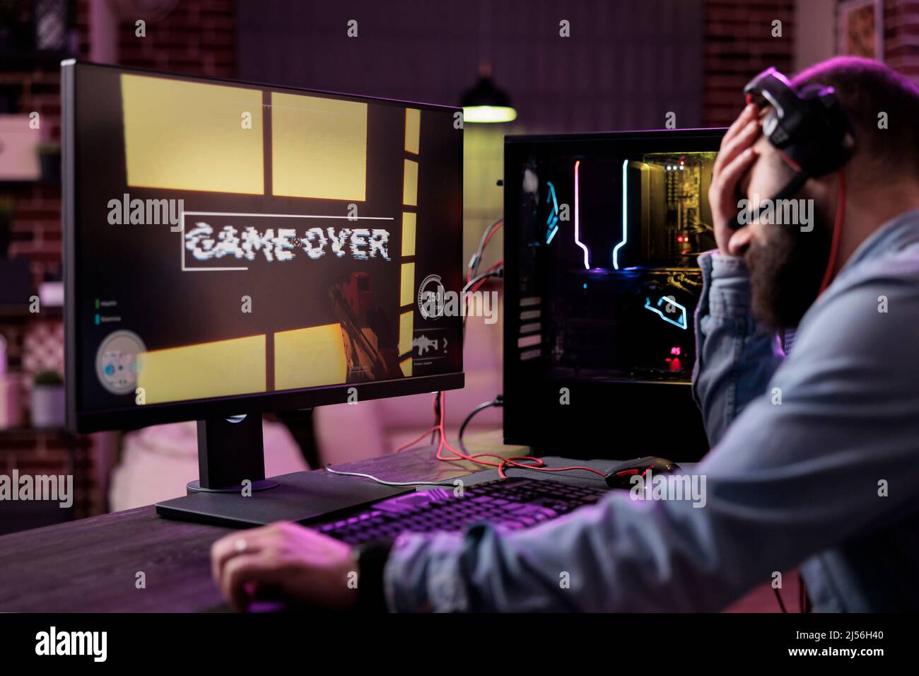 Young adult losing online video games tournament on stream, feeling sad and frustrated. Displeased male player looking at lost action gaming championship on computer, live gameplay. Stock Photo