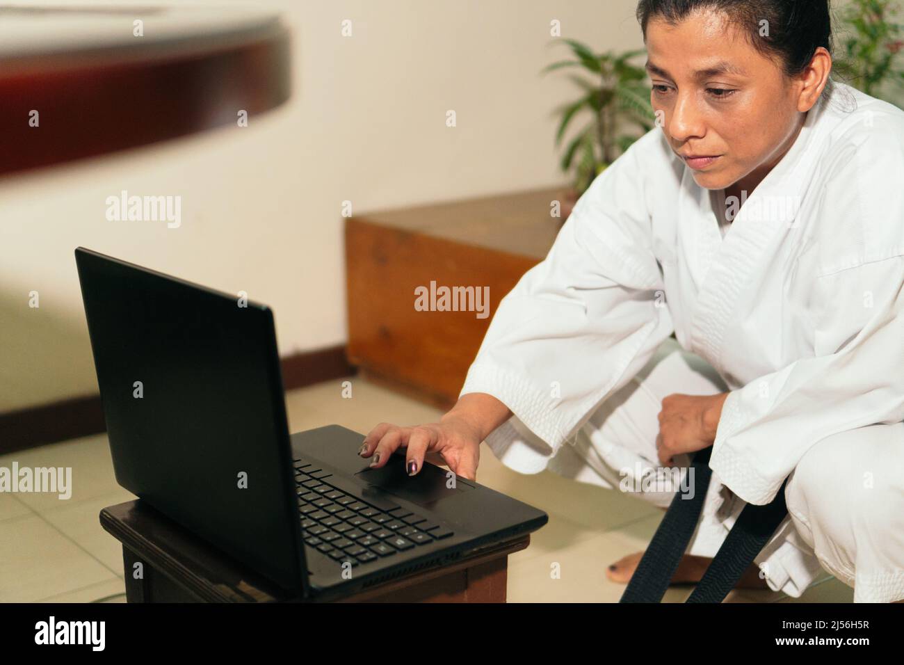 Hispanic Woman preparing computer for karate class at home Stock Photo