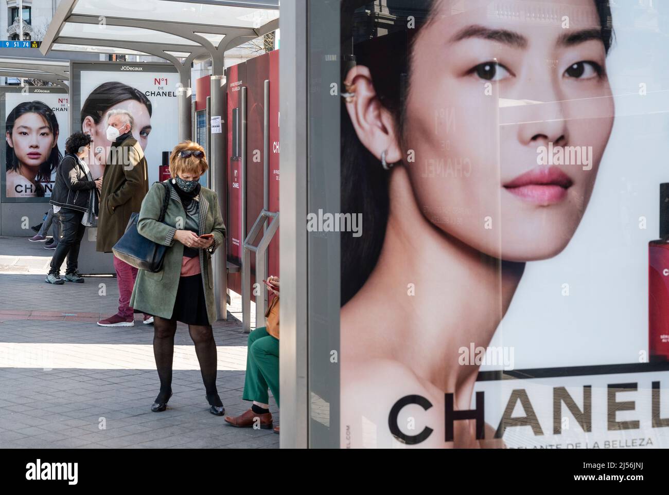 Commuters wait at a bus stop decorated with a commercial advertisement from  the French multinational clothing and beauty products brand Chanel in  Spain. (Photo by Xavi Lopez / SOPA Images/Sipa USA Stock