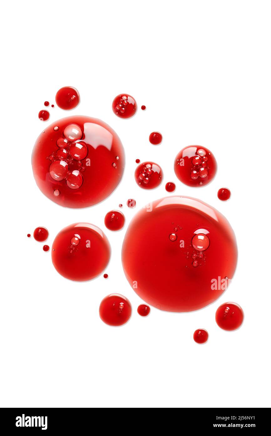 Drops of red cosmetic product on white background Stock Photo - Alamy