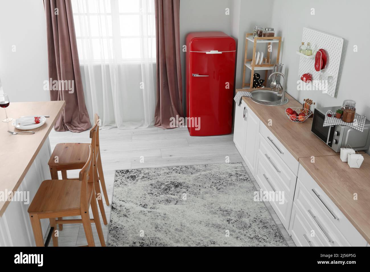 Interior of light kitchen with red fridge, white counters and pegboard ...