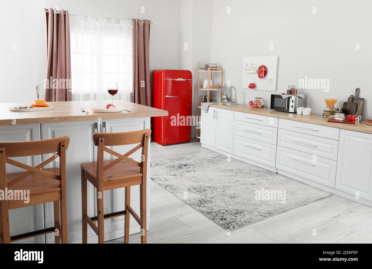 Interior of light kitchen with red fridge, white counters and pegboard ...