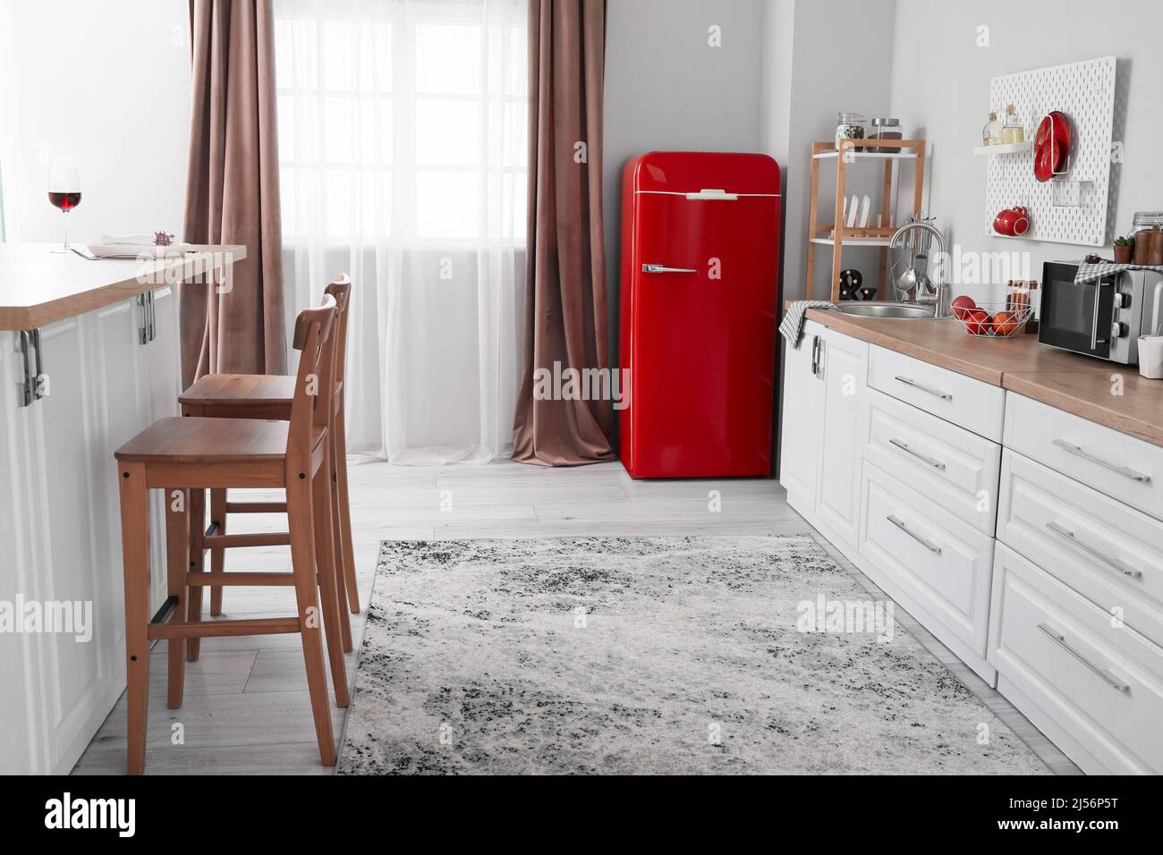 Interior of light kitchen with red fridge, white counters and chairs ...