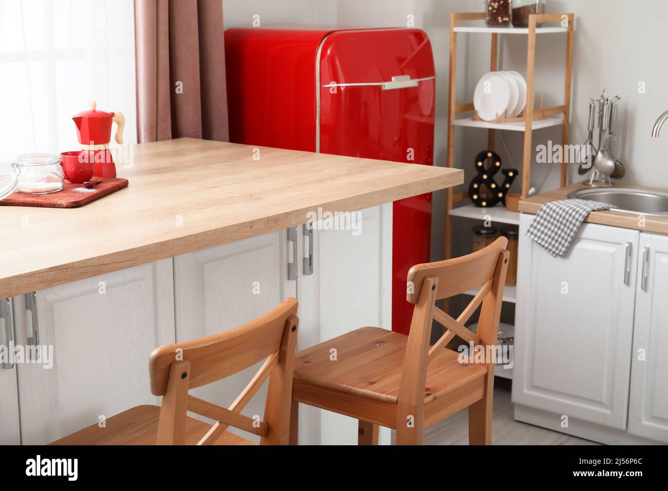 Interior of light kitchen with retro fridge, white counters and chairs ...