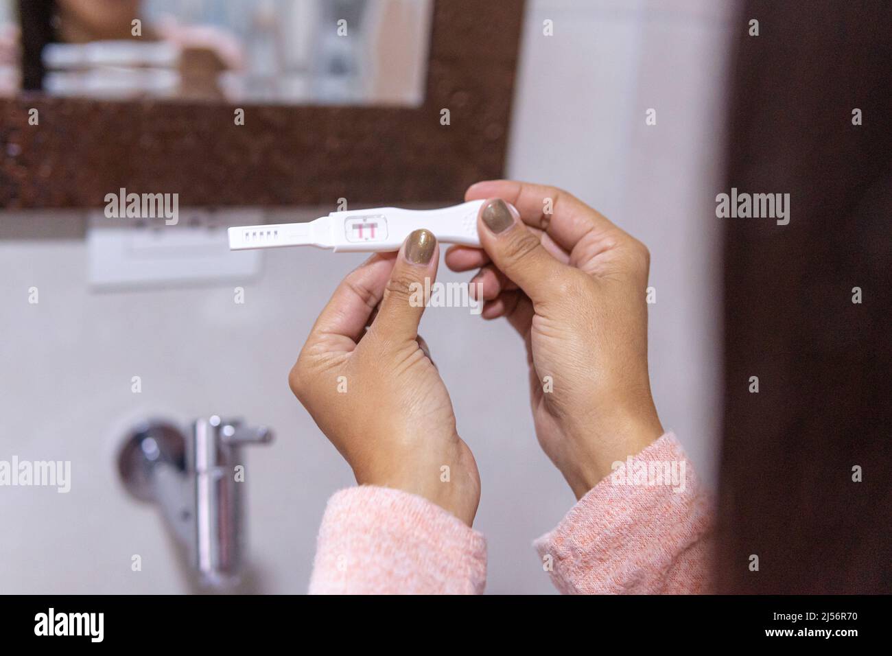 Close-up of unrecognizable woman's hands with a positive pregnancy test ...