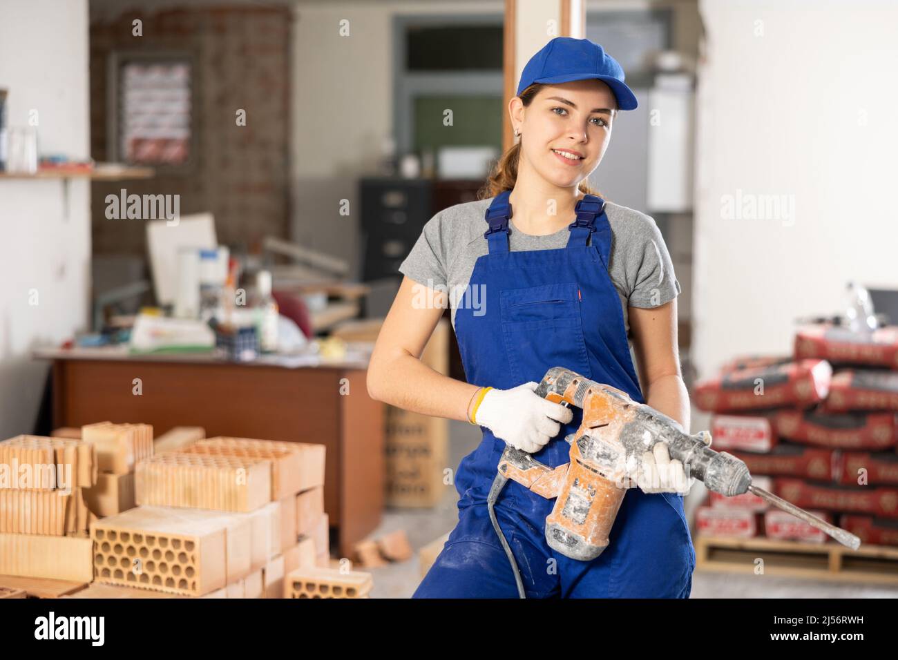 Young woman construction worker standing inside apartment Stock Photo