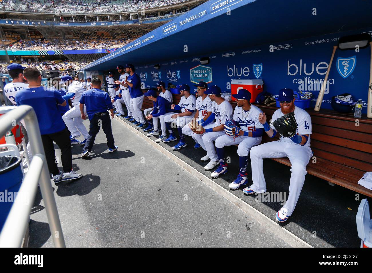 Los Angeles Dodgers players sit in the dugout prior to an MLB regular