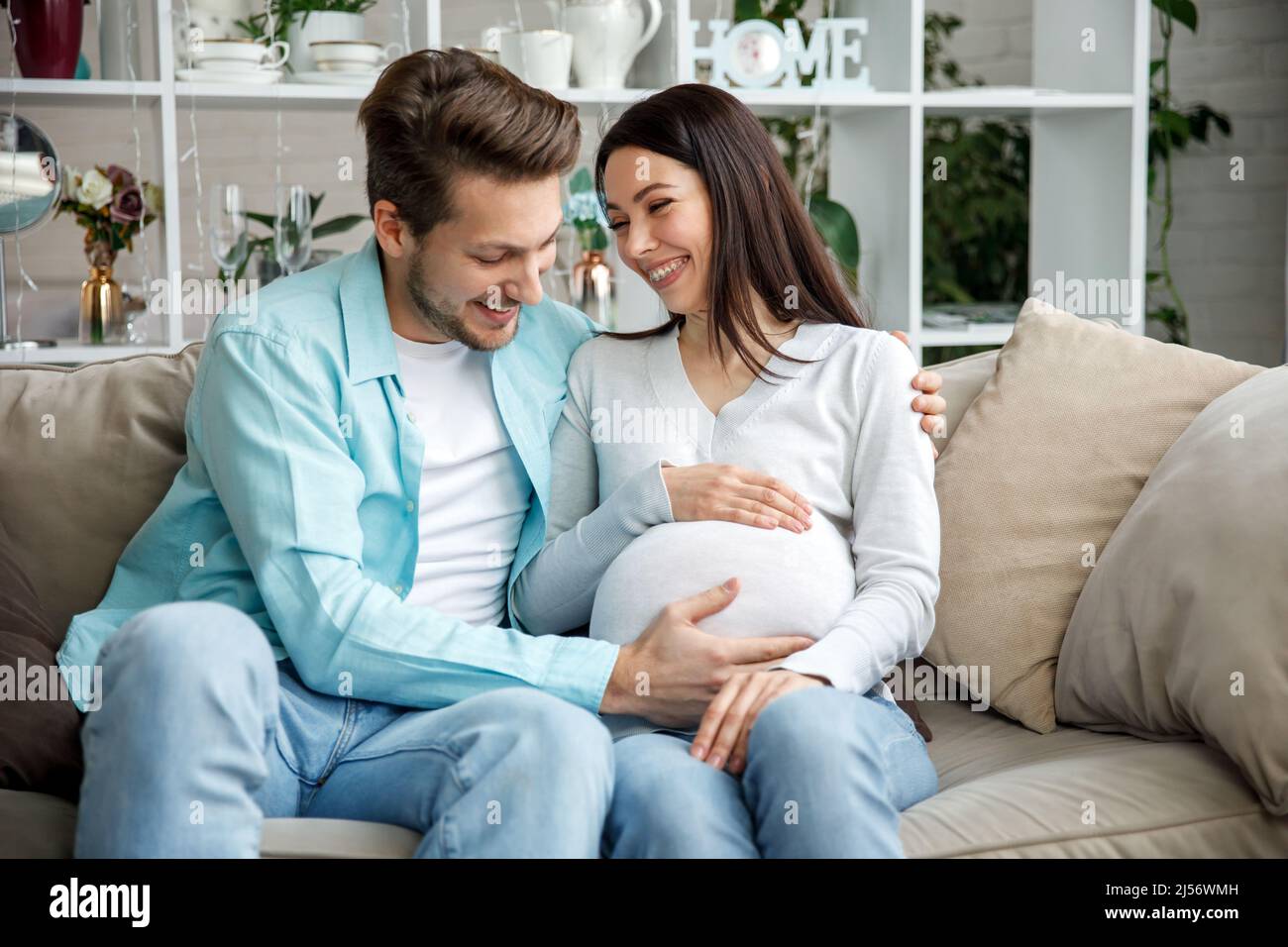 Couple expecting a baby while husband caresses the belly of his pregnant woman.. Stock Photo