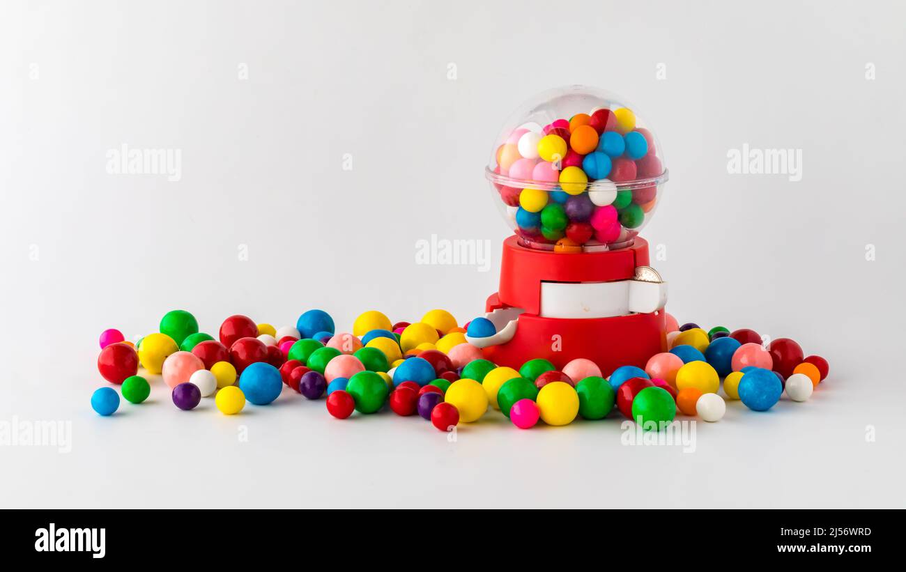 A plastic toy gum ball machine filled and surrounded by gum balls. Stock Photo