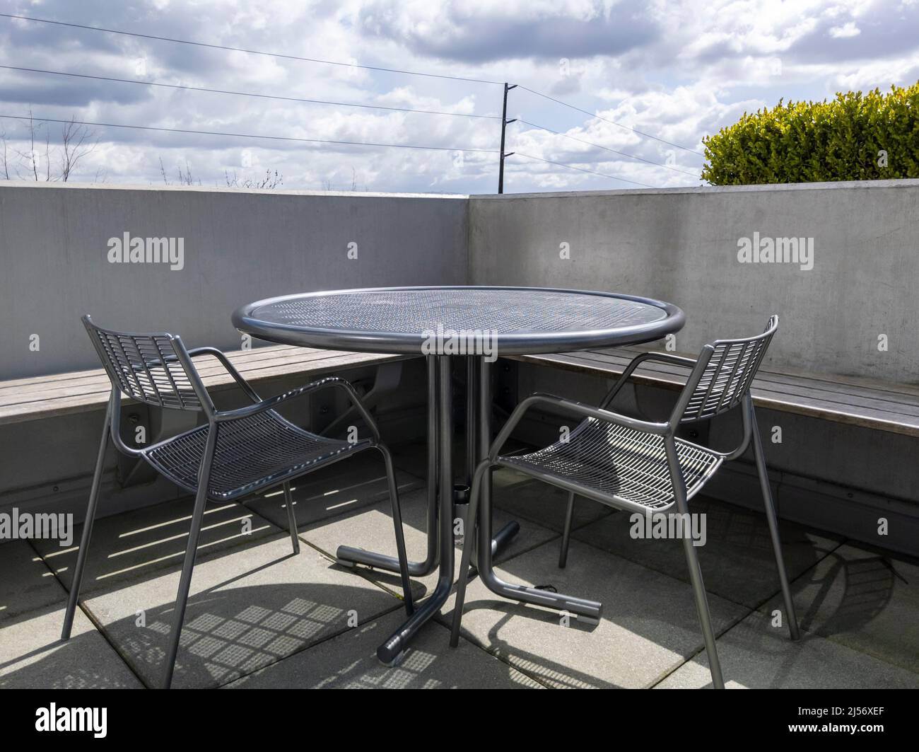 View of a rooftop balcony with a round, metal table and two chairs, overlooking downtown Bellevue, WA Stock Photo