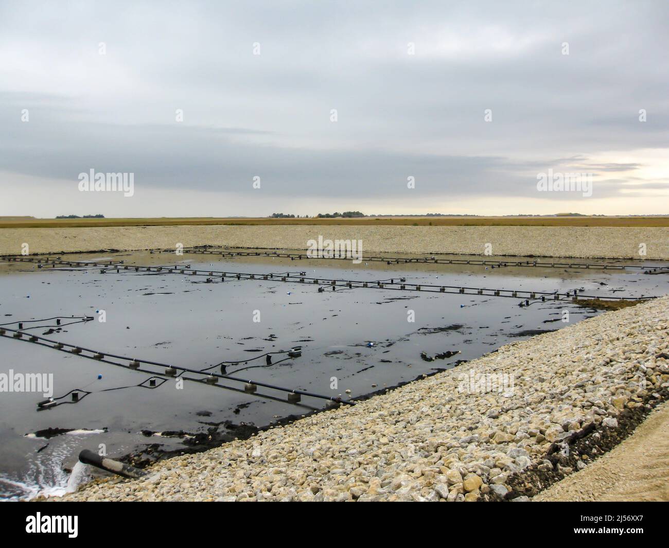 Installation of aeration lines for fine bubbles in an aerobic wastewater treatment lagoon construction project. Stock Photo