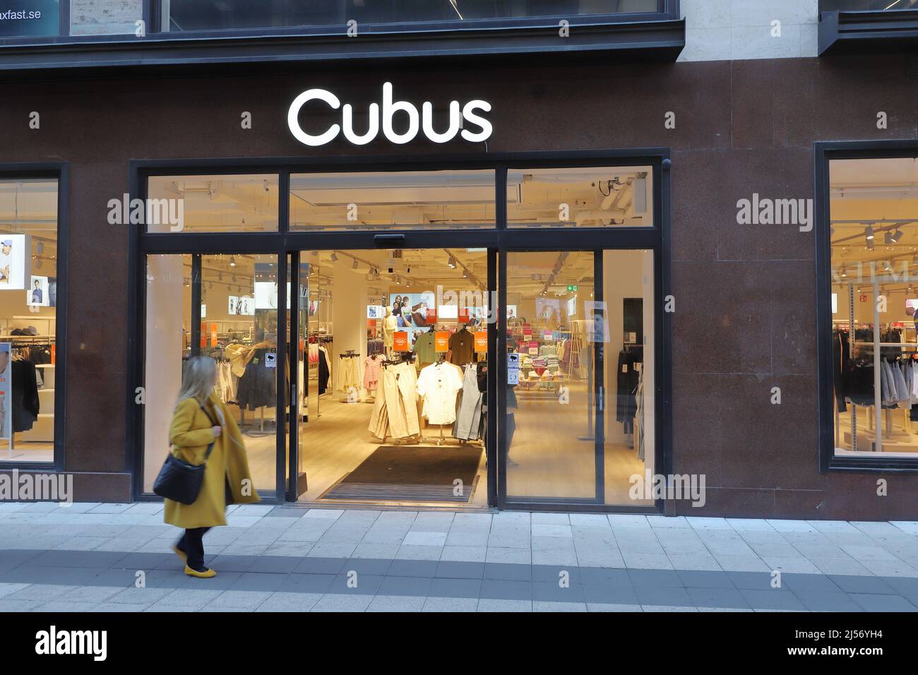 Stockholm, Sweden - April 19, 2022: Exterior view of the Cubus clothing store with a female person wolking by on the Drottninggatan street. Stock Photo