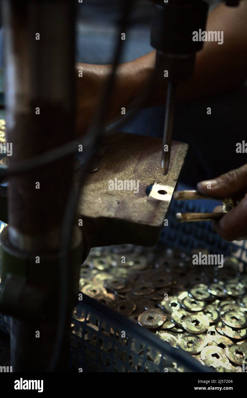 Production of traditional Balinese coins with hollow known as 'pis bolong/jinah bolong/uang kepeng' in Kamasan village, Klungkung, Bali, Indonesia. Used in transactions across Bali in the past, the coins are nowadays essential in traditional religious rituals in the 'Island of Gods'. Stock Photo