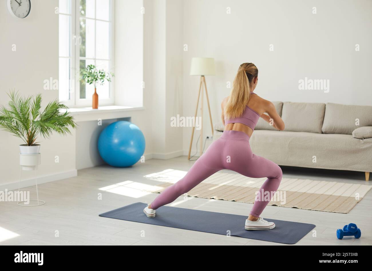 Young woman does morning exercises and stretching during sports training at home. Stock Photo