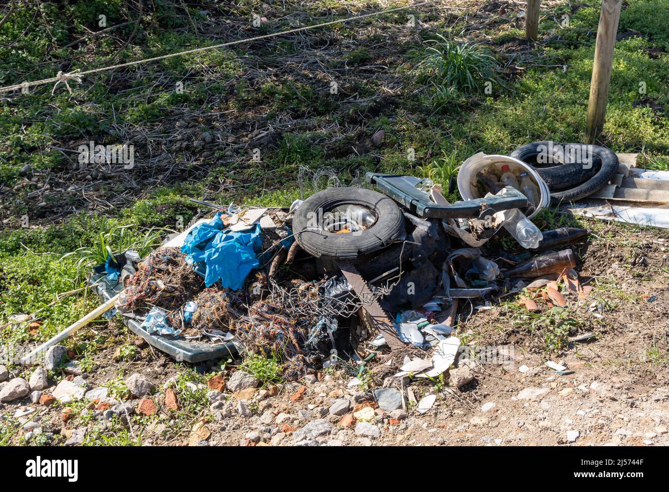 illegal garbage deposition in the nature, old tires , bottles and plastic, environmental pollution Stock Photo