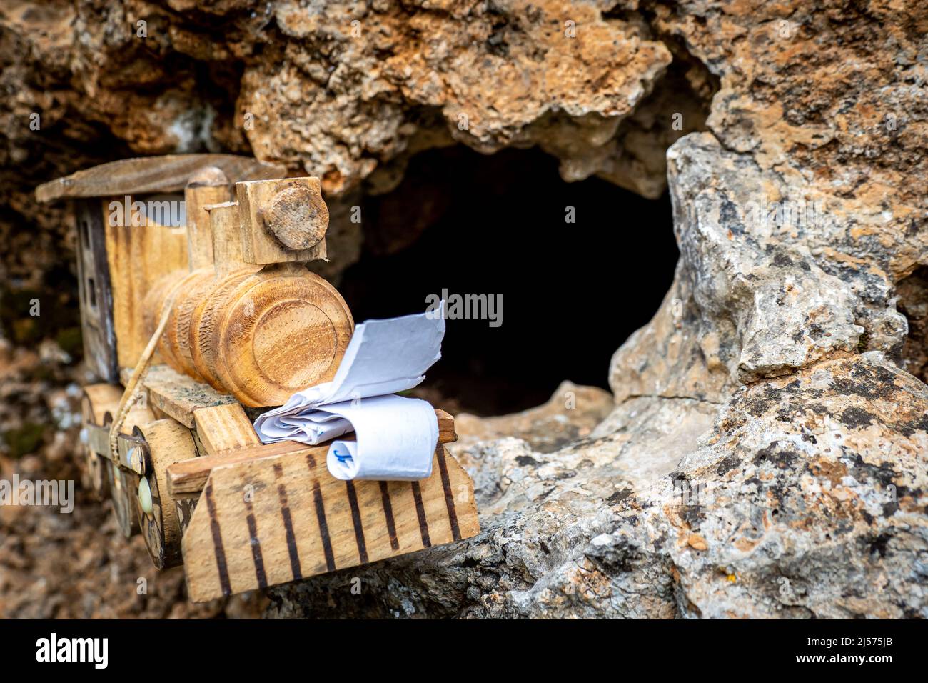 Arrangement of a successful geocaching discovery.  A crafted small toy locomotive geocaching container with a logbook inside hidden in a rock hole Stock Photo