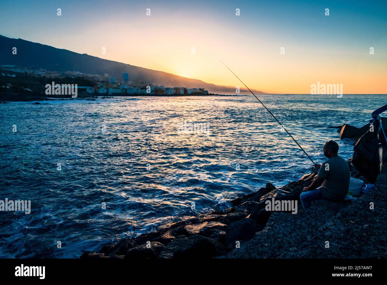 Fishing off the Atardecer during sunset on Playa Jardin in the city of Puerto de la Cruz in the north of Tenerife Canary Islands Stock Photo