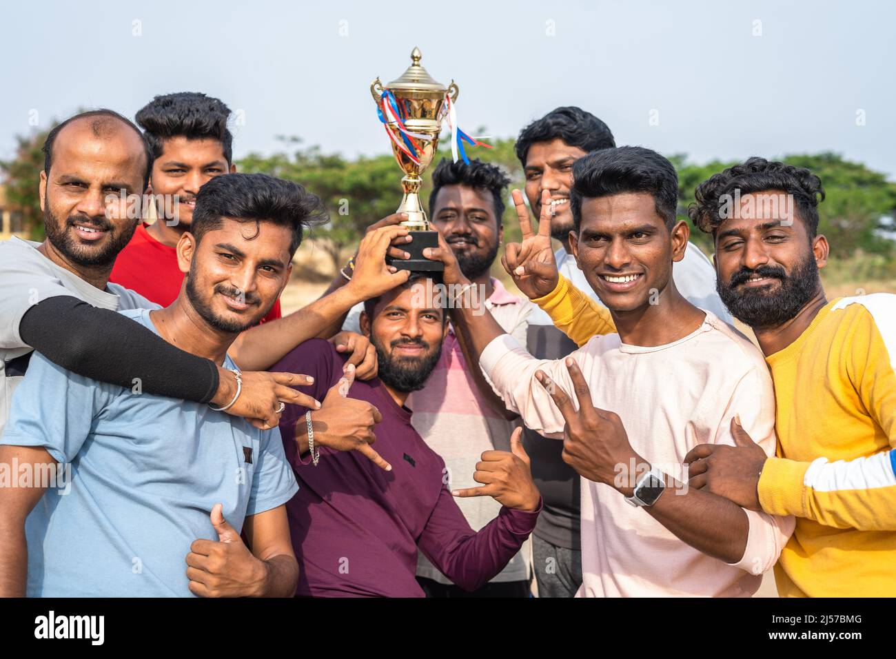group of cricker players celebrating victory of cricket match by holding trophy and by lifting captain - concept of excitement, championship and Stock Photo