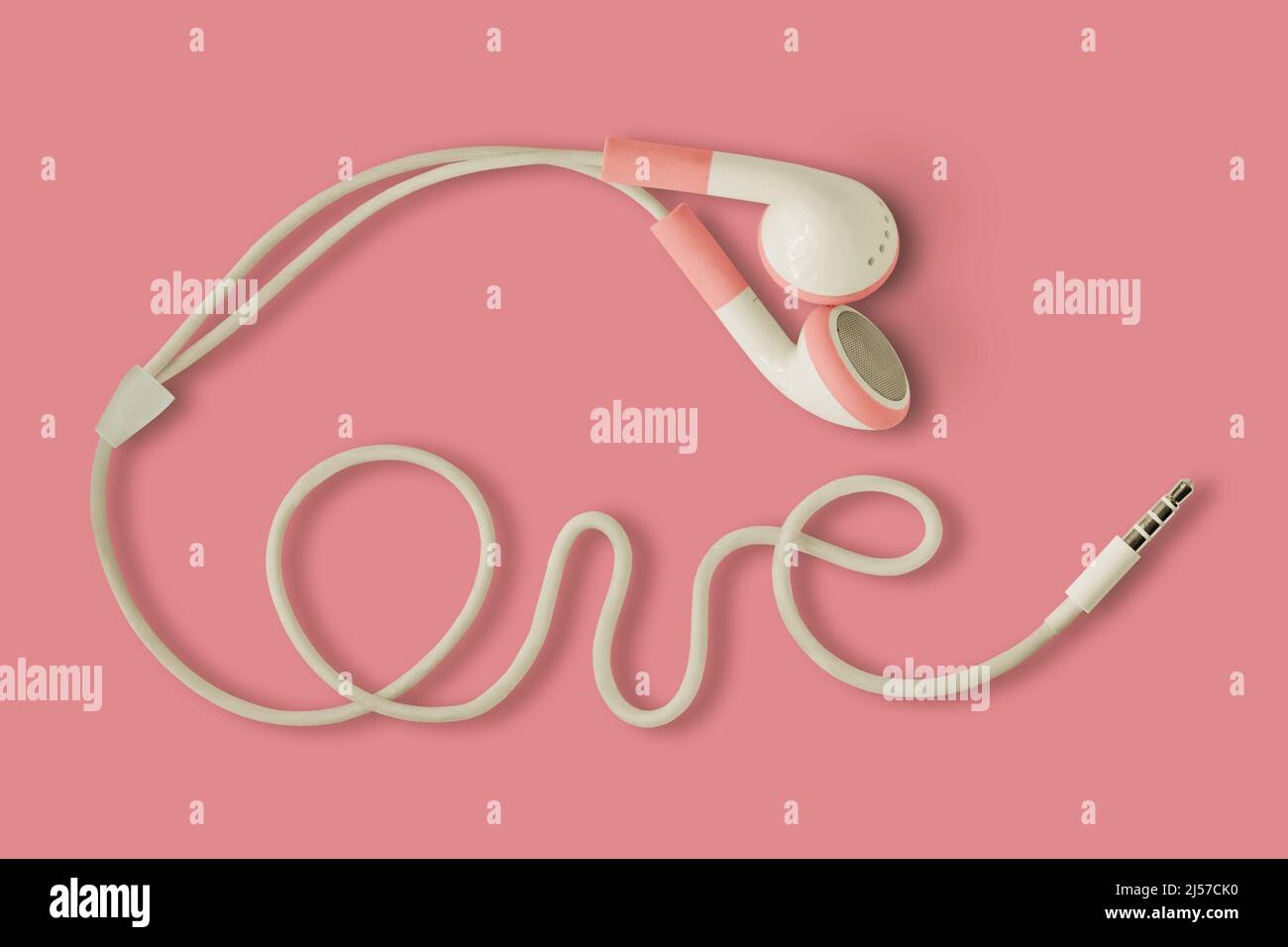 Pink earphones and the word Love written with cable on pink background - Concept of love, listening and support to women Stock Photo