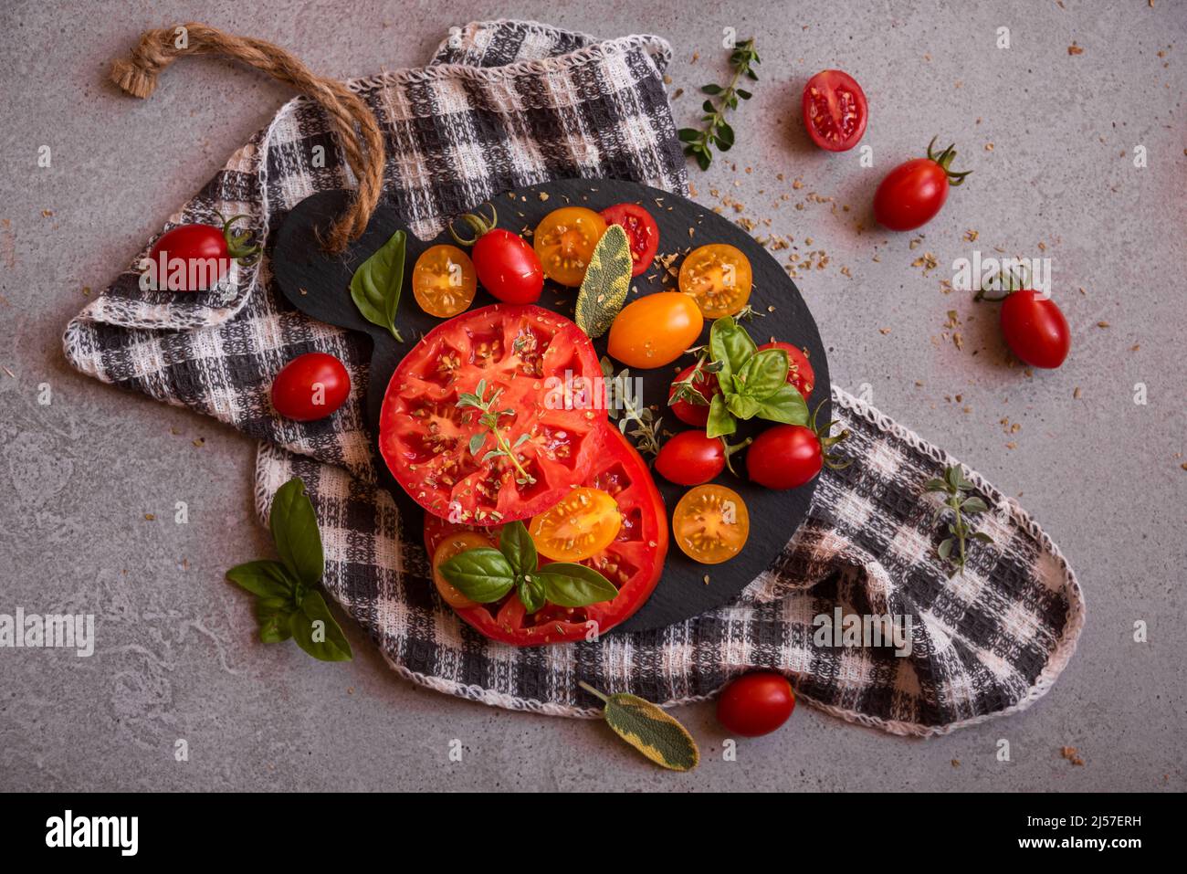 Various tomatoes whole and cut served with basil Stock Photo - Alamy
