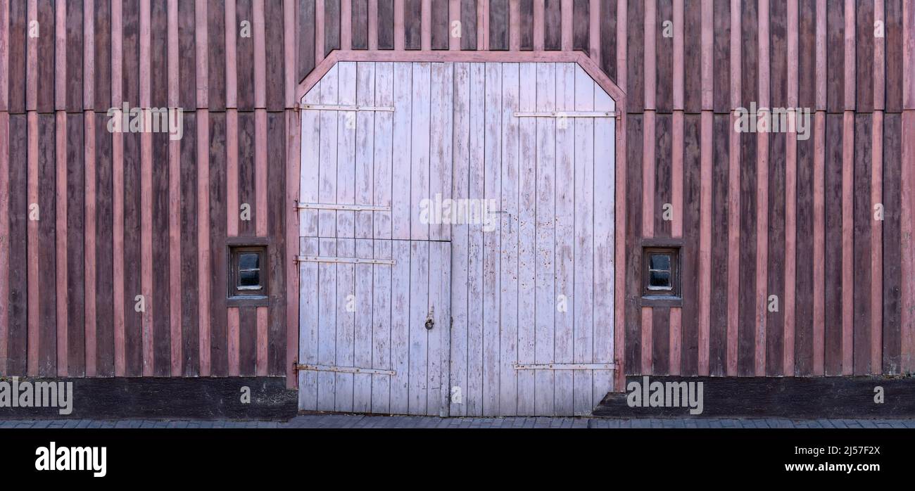 Old wooden facade with purple stripe pattern and a large gate Stock Photo