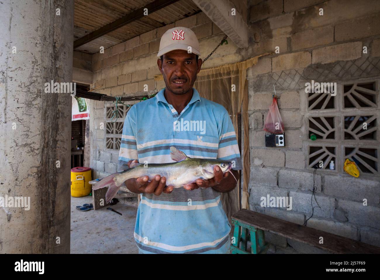 Panamanian man with a fish outside his house beside Rio Grande, Cocle province, Republic of Panama, Central America. Stock Photo