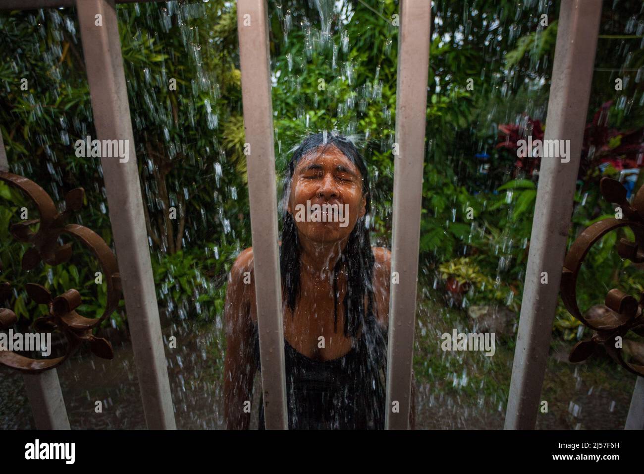 A panamanian woman is taking a shower in the rainwater from the roof of the house in Penonome, Cocle province, Republic of Panama, Central America. Stock Photo